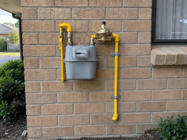 Exterior brick wall with gas meter and new yellow gas pipework in Glenmore Park